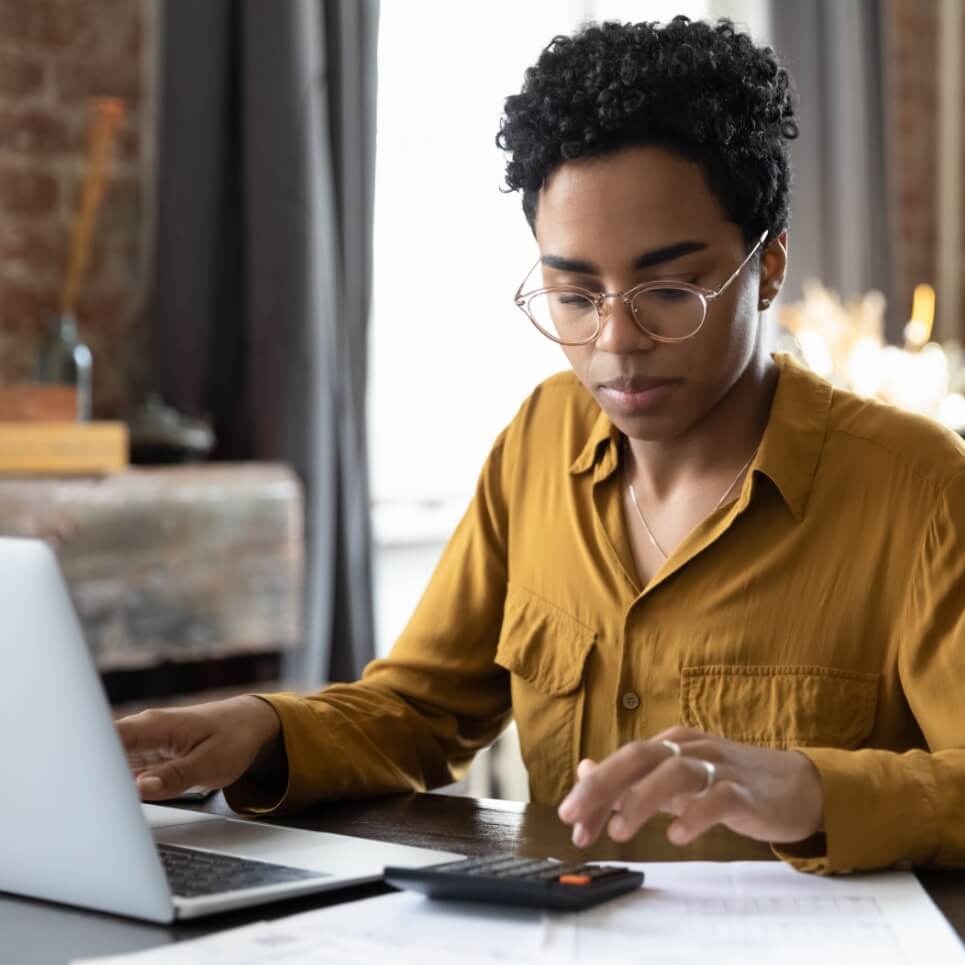 Image showing a woman using a calculator sitting in front of her laptop