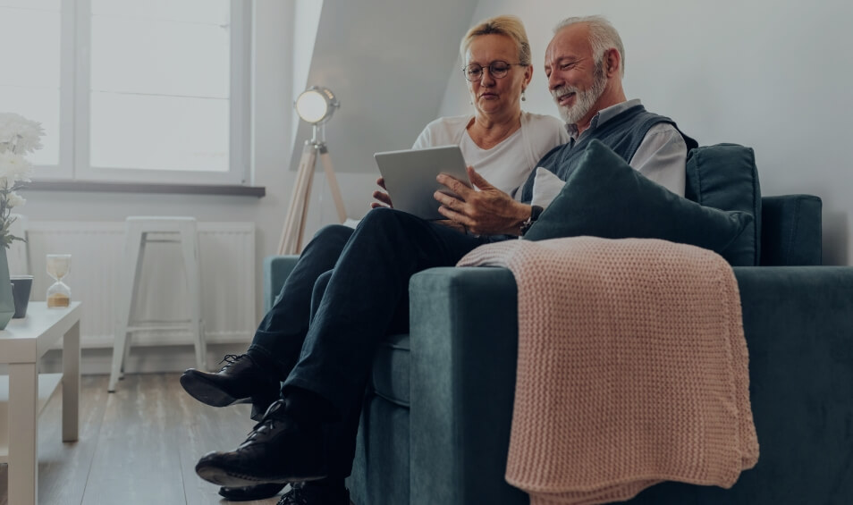 Image showing an older couple sitting on their sofa looking at a tablet together