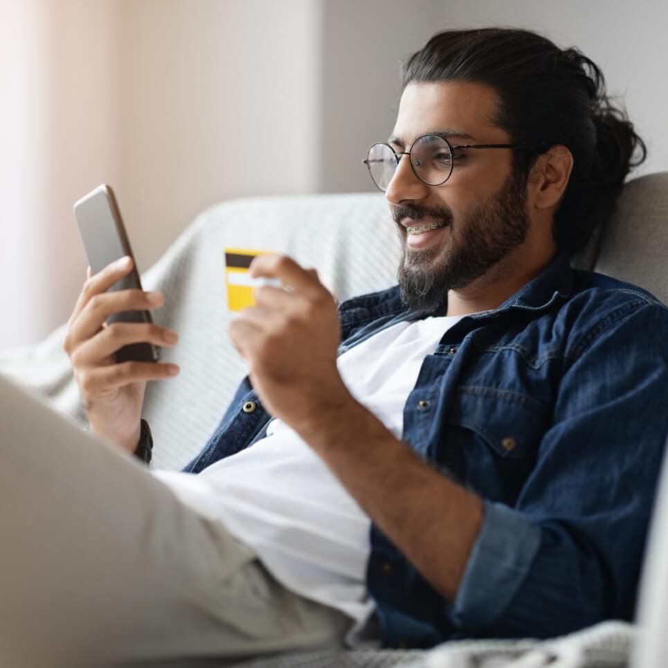 Image showing a man holding a bank card and his phone