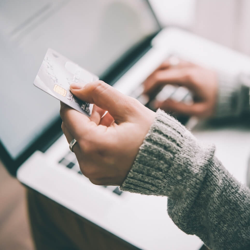 Image showing a close up of someone holding a payment card while typing on their laptop